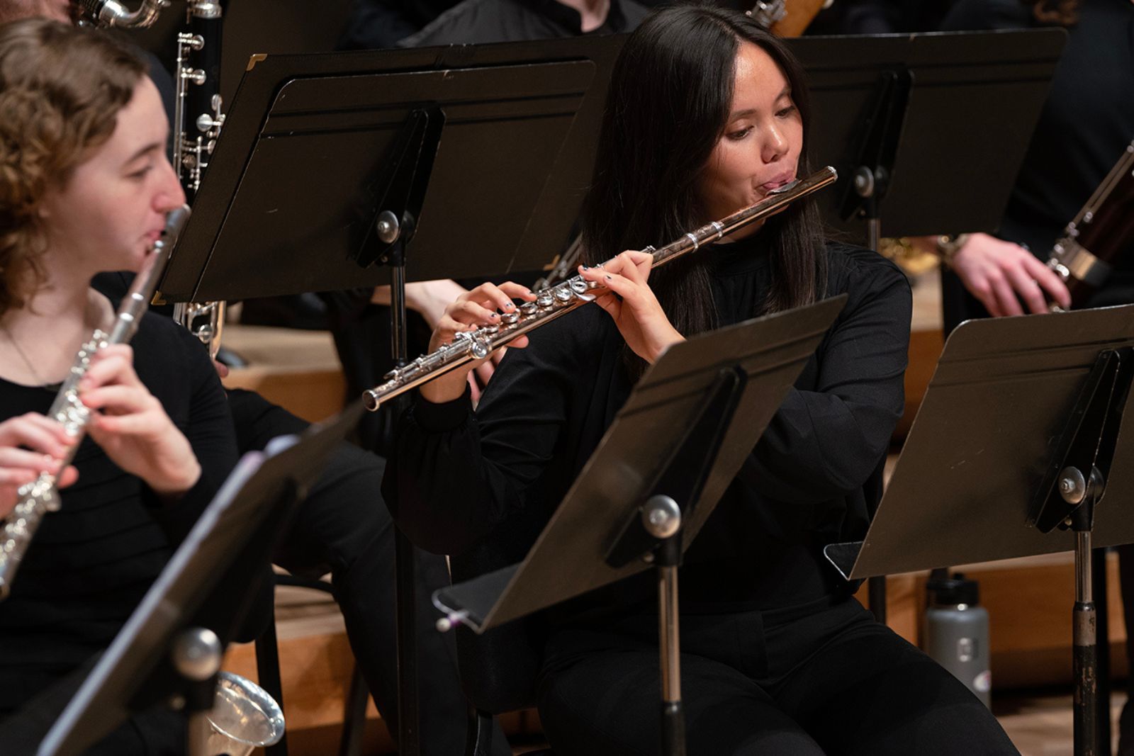 Two members of the UMD Wind Orchestra play flute during a concert.