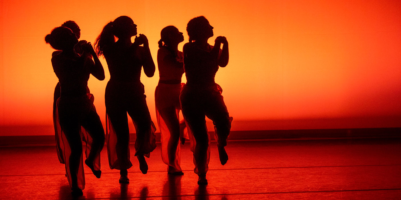 Dancers on an orange and red lit stage.