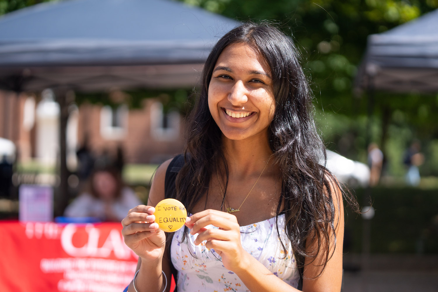 A student holds a button they made at the VOTE (Fearlessly) pop-up that says "I vote for equality."