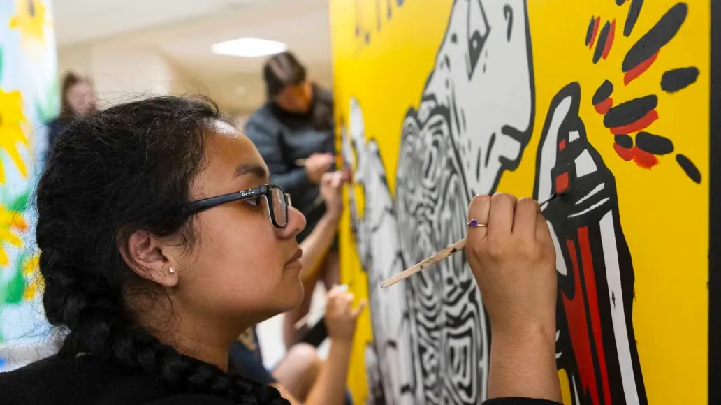 A student paints the Terp Takes Action mural.