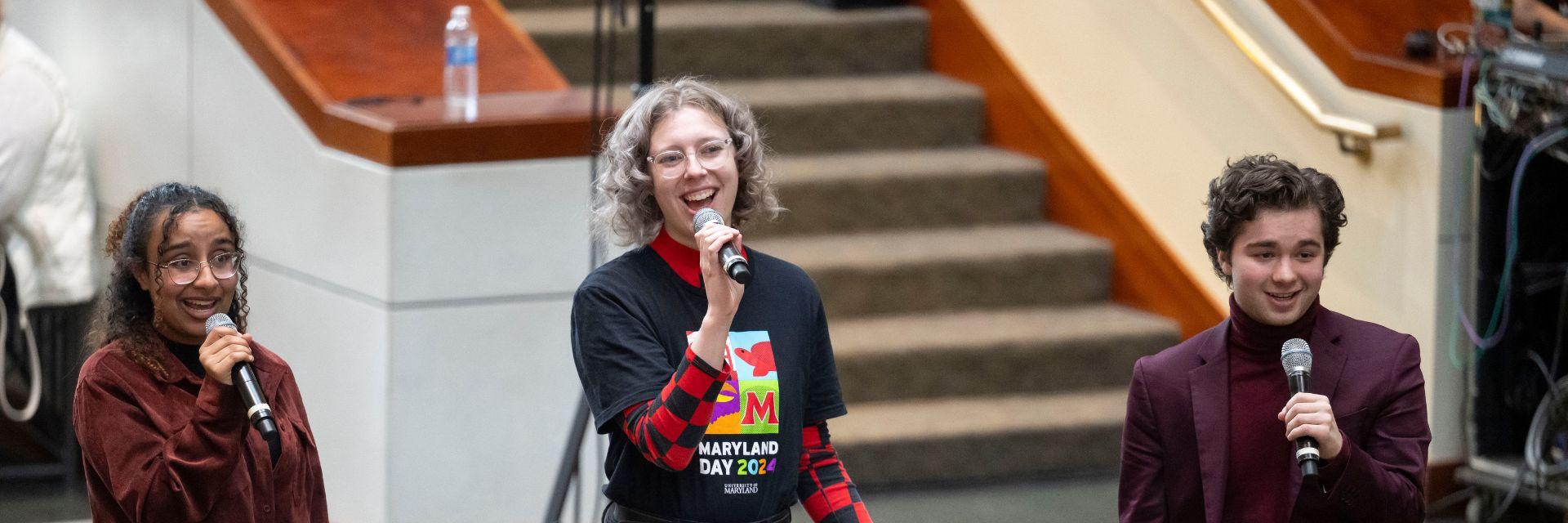 Three students with microphones perform at Maryland Day.