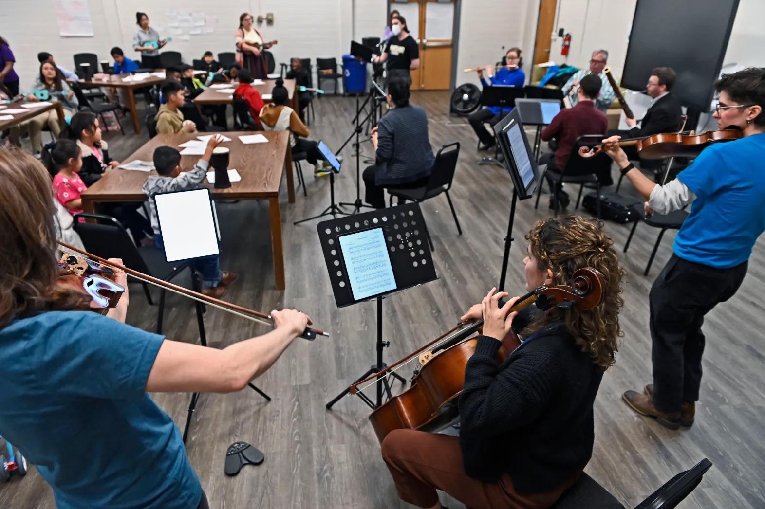 Musicians and children play music together during a workshop.