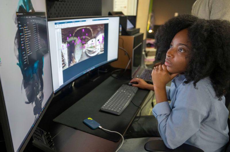 Two students look at immersive media displayed on a computer screen.