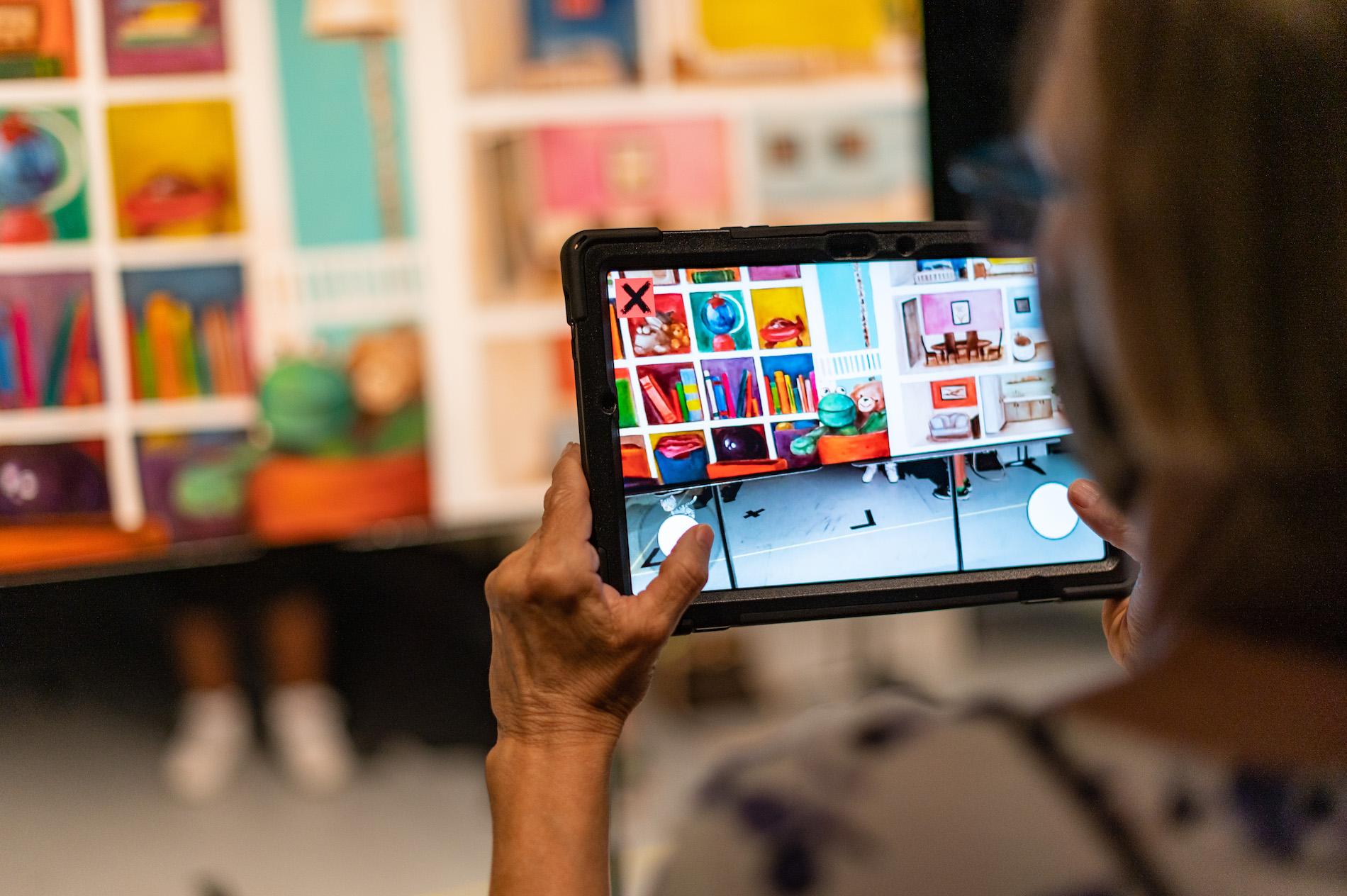A person looks at artwork through an ipad. 
