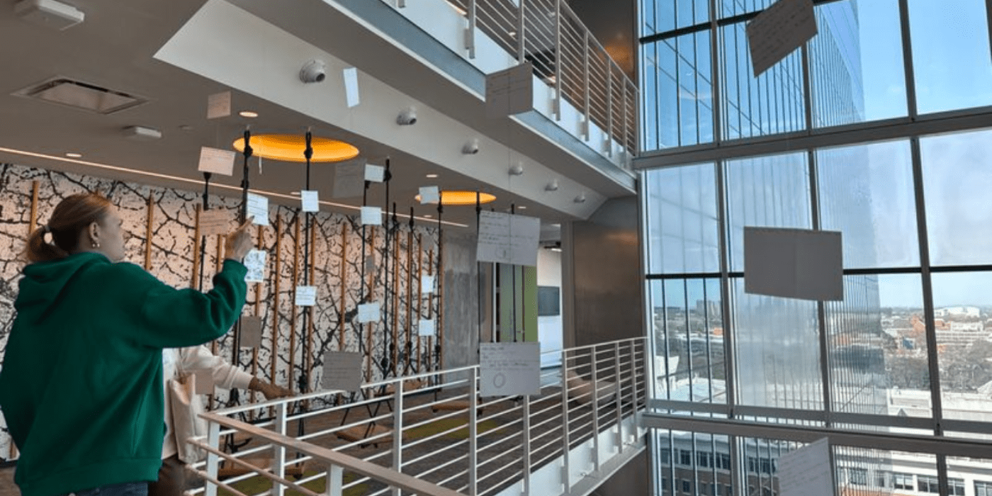 A student looks at a hanging installation on a balcony.
