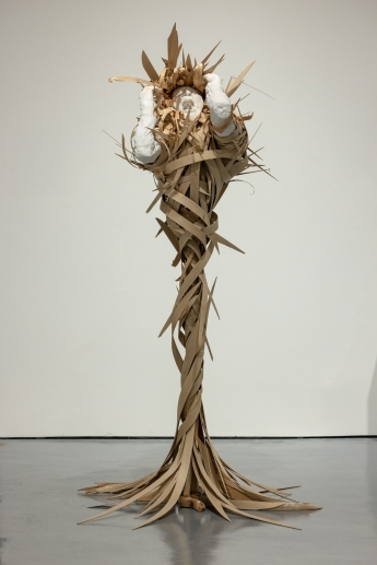 A huge sculture of a screaming person made of using a wooden armature, an old hoodie, plaster bandages, casting with alginate and plaster, and strips of wood. 